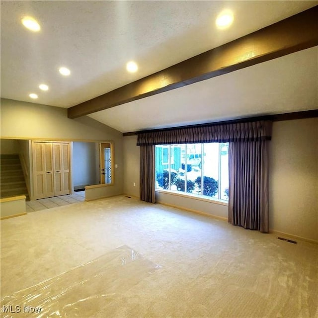 unfurnished living room featuring light carpet and vaulted ceiling with beams