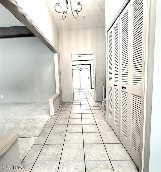 hallway featuring light tile patterned flooring and a chandelier