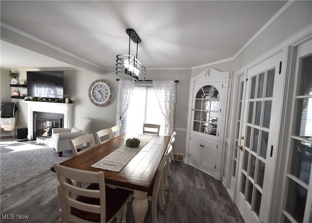 dining room featuring a fireplace, a notable chandelier, crown molding, and dark hardwood / wood-style flooring