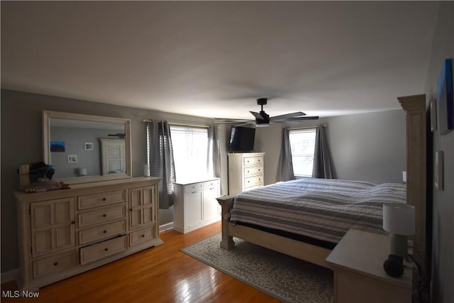 bedroom with ceiling fan, light hardwood / wood-style flooring, and multiple windows