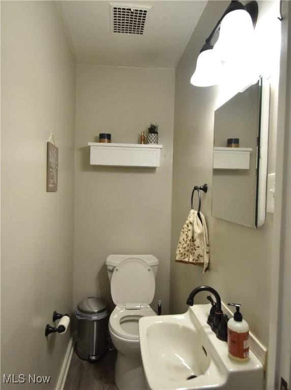 bathroom featuring toilet, wood-type flooring, and sink