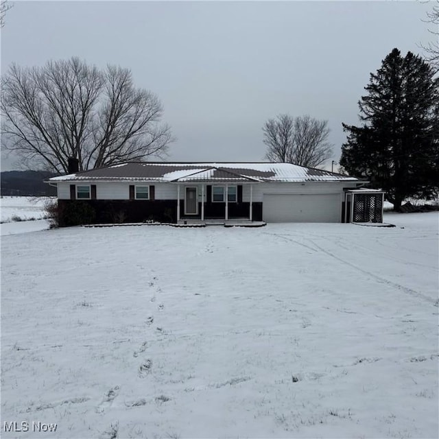 snow covered back of property featuring a garage