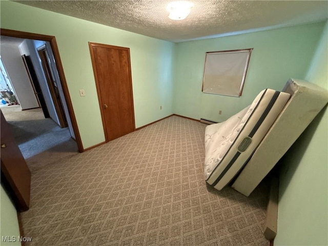 bedroom with a closet, light colored carpet, a textured ceiling, and a baseboard heating unit