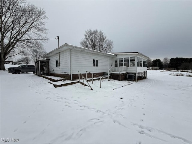 snow covered property with a sunroom