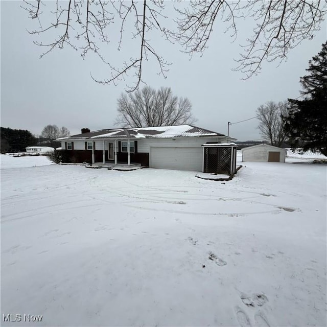 snow covered back of property with central AC unit and a garage