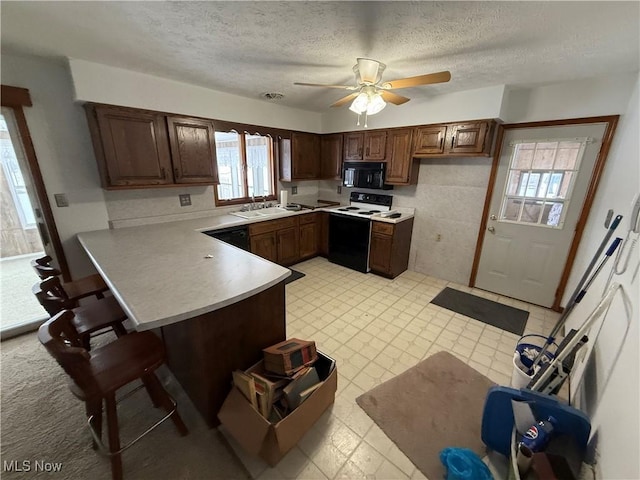 kitchen featuring black appliances, sink, ceiling fan, a textured ceiling, and kitchen peninsula