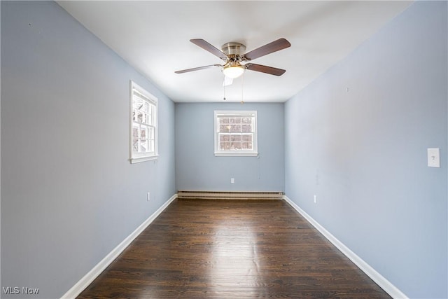 spare room featuring ceiling fan, dark wood-type flooring, and a baseboard heating unit