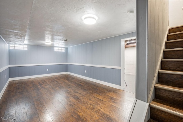 basement featuring dark hardwood / wood-style flooring and a textured ceiling