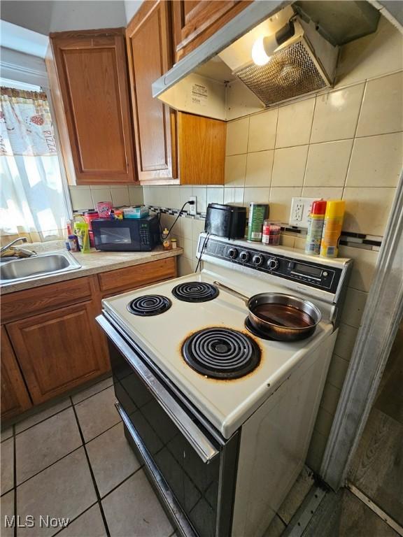 kitchen with sink, backsplash, ventilation hood, electric range, and light tile patterned floors