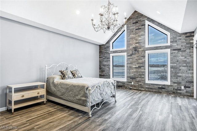 bedroom with a notable chandelier, hardwood / wood-style flooring, and high vaulted ceiling