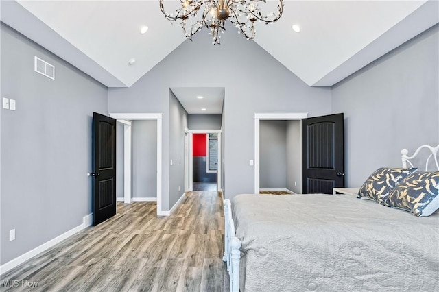 unfurnished bedroom with wood-type flooring, a chandelier, and high vaulted ceiling