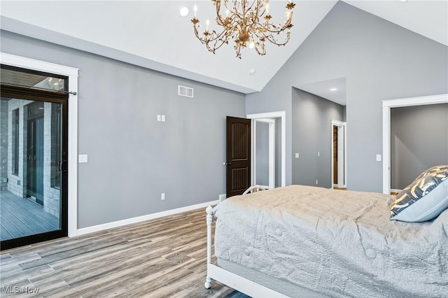 bedroom featuring hardwood / wood-style floors, a notable chandelier, high vaulted ceiling, and ensuite bath