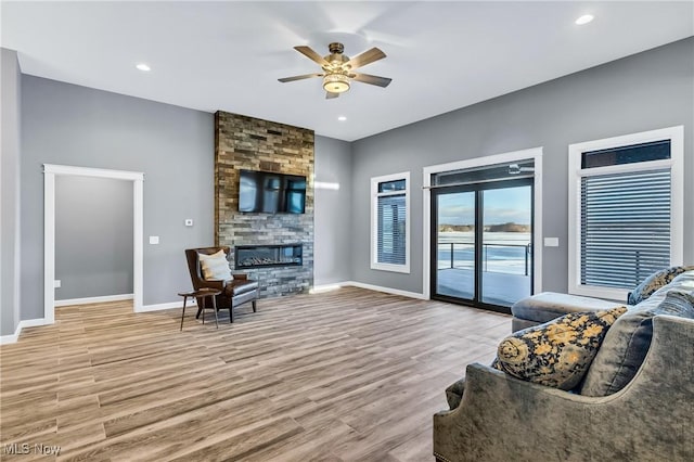 living room with ceiling fan, a fireplace, and light hardwood / wood-style floors