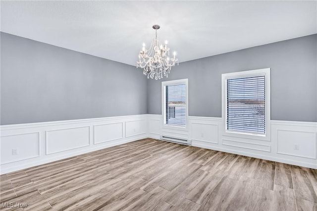 unfurnished room with a notable chandelier and light wood-type flooring