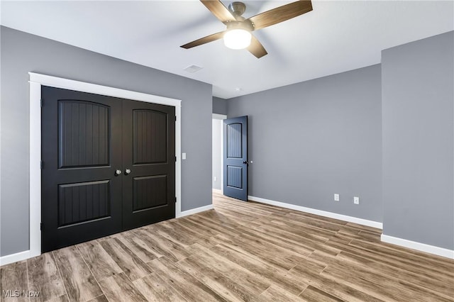 unfurnished bedroom with light hardwood / wood-style floors, a closet, and ceiling fan