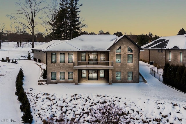 snow covered rear of property featuring a balcony