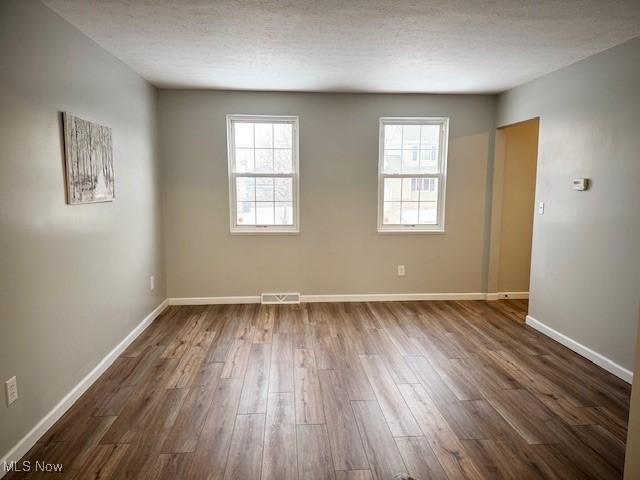 spare room featuring a textured ceiling and dark hardwood / wood-style floors