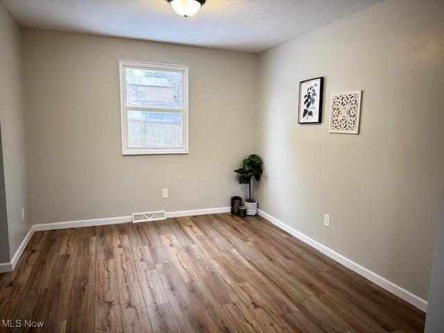 spare room featuring wood-type flooring and a textured ceiling