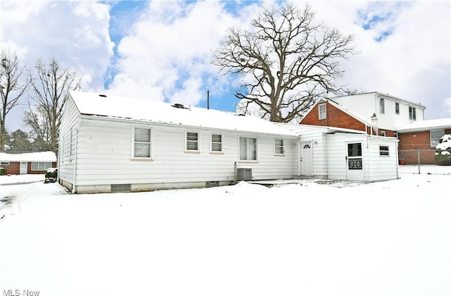 snow covered back of property featuring central AC