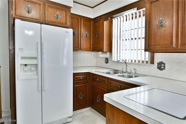 kitchen featuring white refrigerator with ice dispenser, tasteful backsplash, and sink