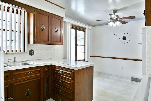 kitchen with ceiling fan, sink, tasteful backsplash, kitchen peninsula, and stovetop