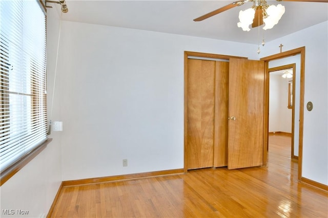 unfurnished bedroom featuring ceiling fan, a closet, and light wood-type flooring