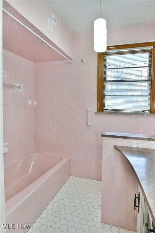 bathroom featuring tile patterned flooring, vanity, washtub / shower combination, and tile walls