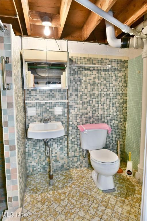 bathroom featuring sink, toilet, and tile walls