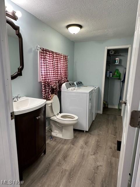 bathroom featuring washer and clothes dryer, vanity, toilet, and wood-type flooring