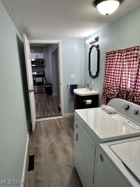 washroom with washer and clothes dryer, dark wood-type flooring, a textured ceiling, and sink