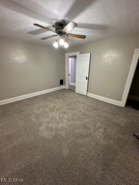 unfurnished bedroom with a textured ceiling, dark carpet, and ceiling fan