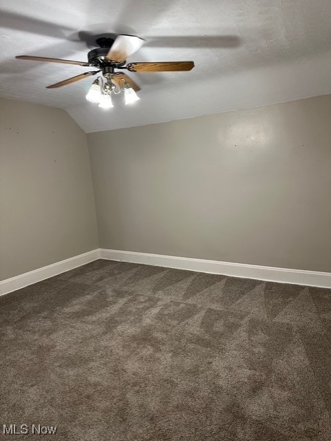 spare room with a textured ceiling, ceiling fan, dark carpet, and lofted ceiling