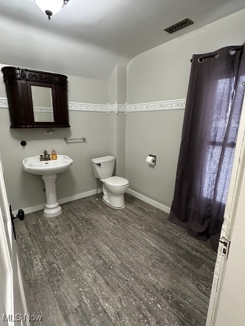 bathroom featuring toilet and wood-type flooring