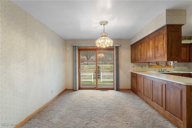 kitchen with light carpet, sink, decorative light fixtures, and a notable chandelier