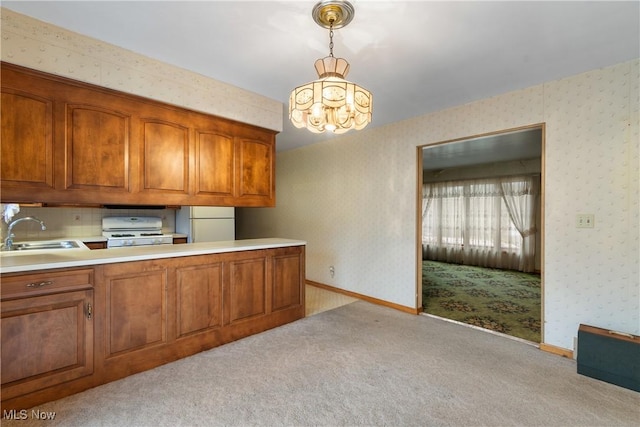 kitchen featuring pendant lighting, light colored carpet, white appliances, and sink