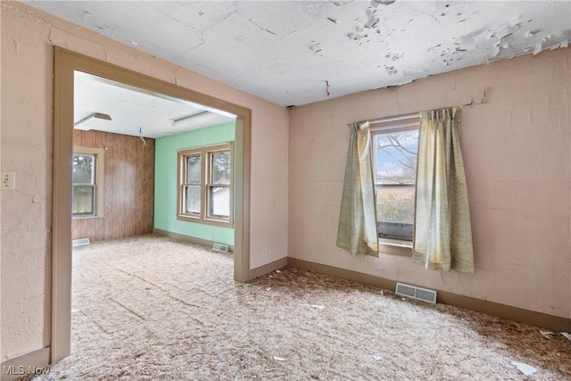 spare room with carpet flooring and wooden walls