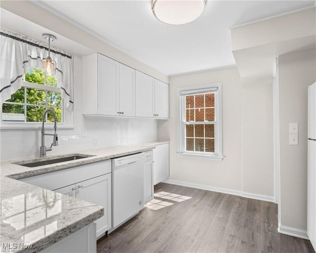 kitchen featuring dishwasher, white cabinets, light stone counters, and sink