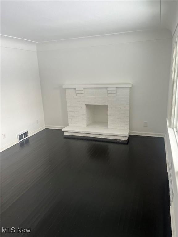 unfurnished living room with a fireplace, dark hardwood / wood-style flooring, and crown molding