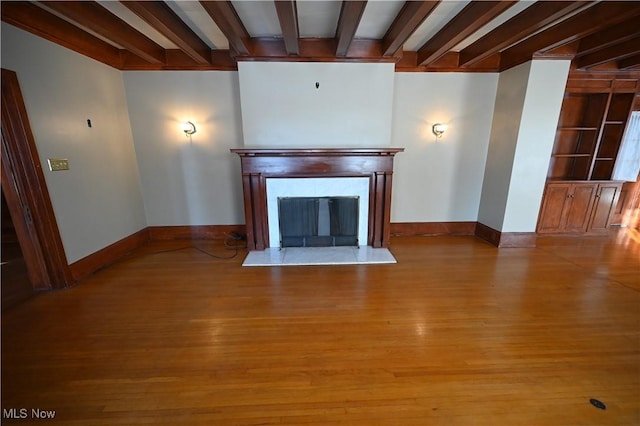 unfurnished living room featuring light hardwood / wood-style floors and beam ceiling