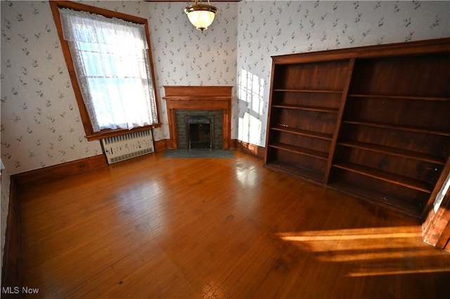 unfurnished living room featuring radiator heating unit and hardwood / wood-style flooring