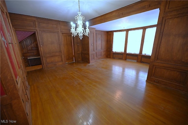 interior space featuring a chandelier, light hardwood / wood-style floors, and wooden walls