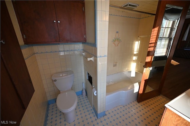 bathroom with toilet, tile walls, and tub / shower combination