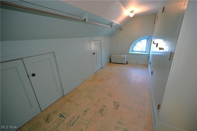 additional living space featuring lofted ceiling and radiator