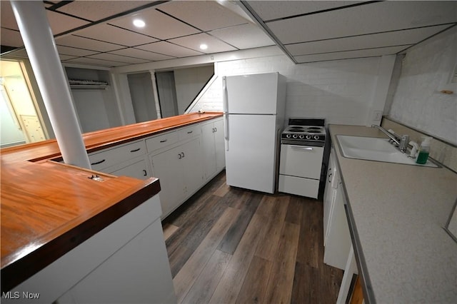 kitchen with stove, white cabinets, sink, dark hardwood / wood-style floors, and white fridge