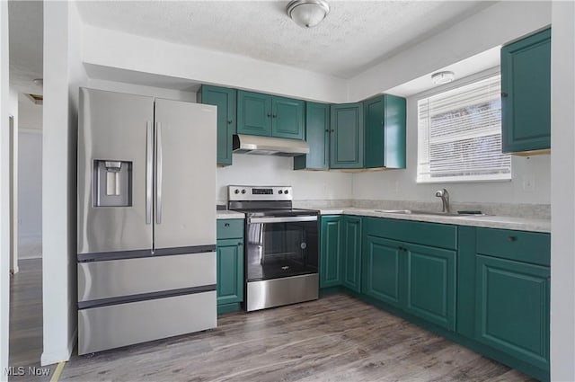 kitchen with hardwood / wood-style floors, sink, stainless steel appliances, and a textured ceiling