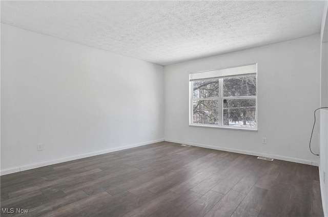 empty room featuring a textured ceiling and dark hardwood / wood-style floors