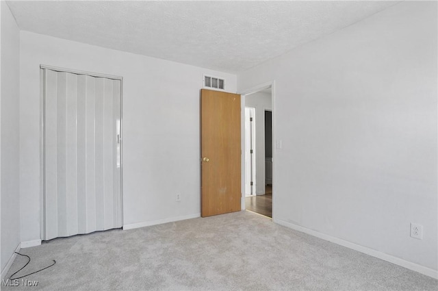 unfurnished bedroom with a closet, light colored carpet, and a textured ceiling