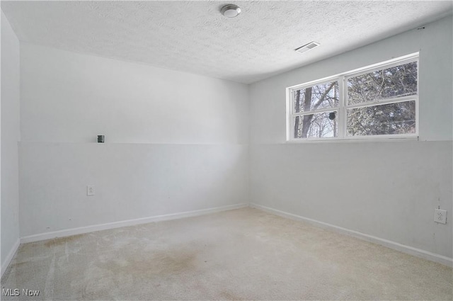 empty room with a textured ceiling and light carpet