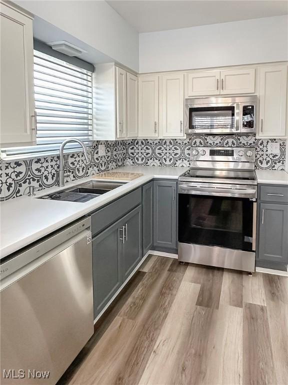 kitchen featuring backsplash, gray cabinetry, stainless steel appliances, sink, and dark hardwood / wood-style floors