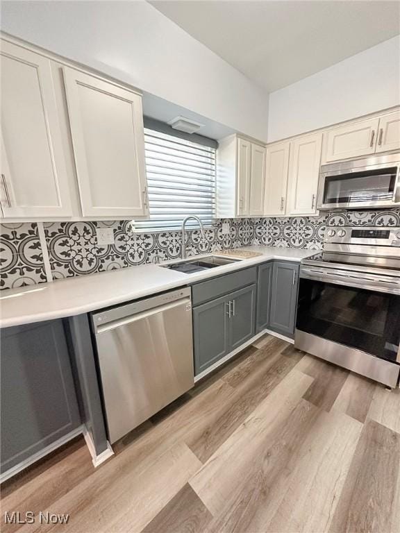 kitchen featuring sink, white cabinets, stainless steel appliances, and light wood-type flooring